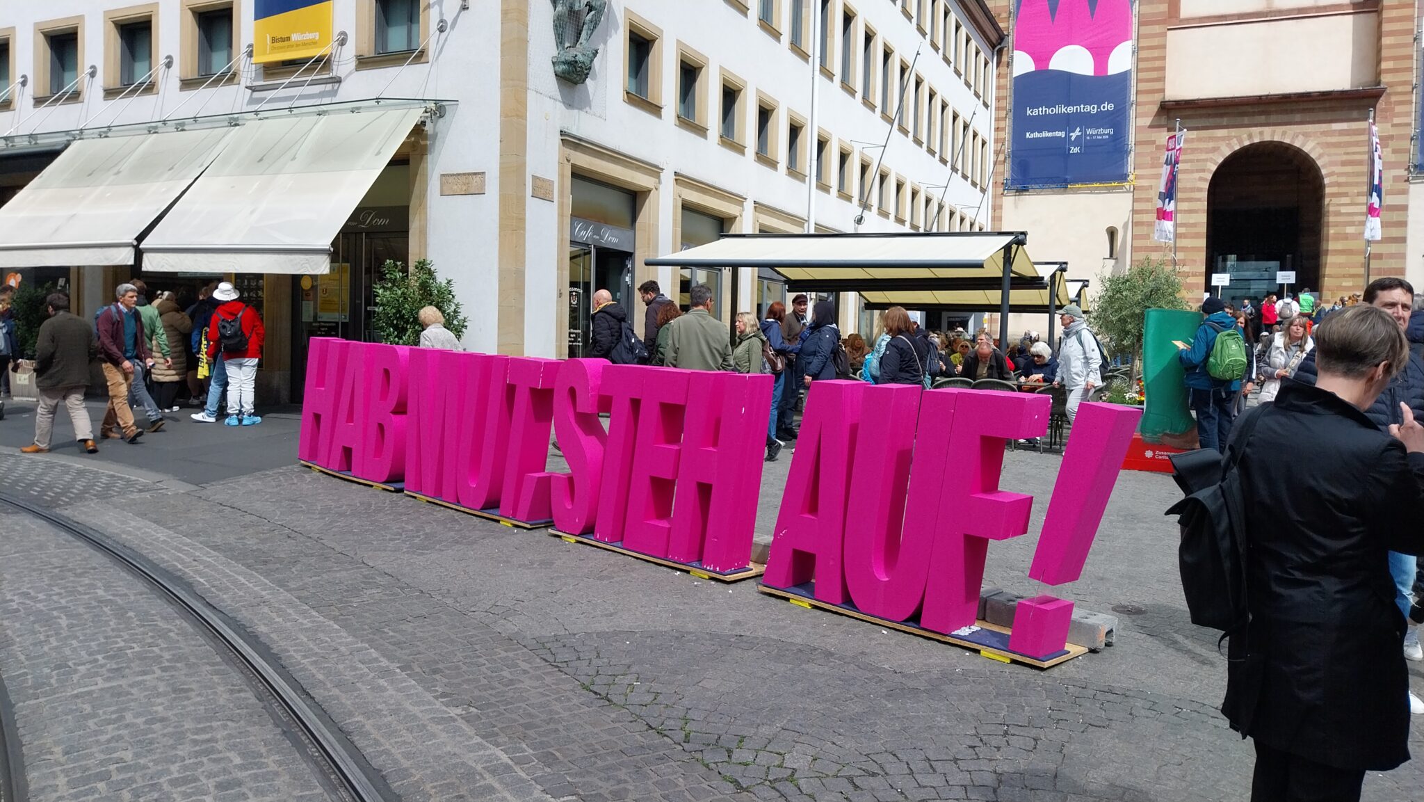 "Hab Mut, steh auf", große Buchstaben stehen in pink an einem zentralen Ort in Würzburg